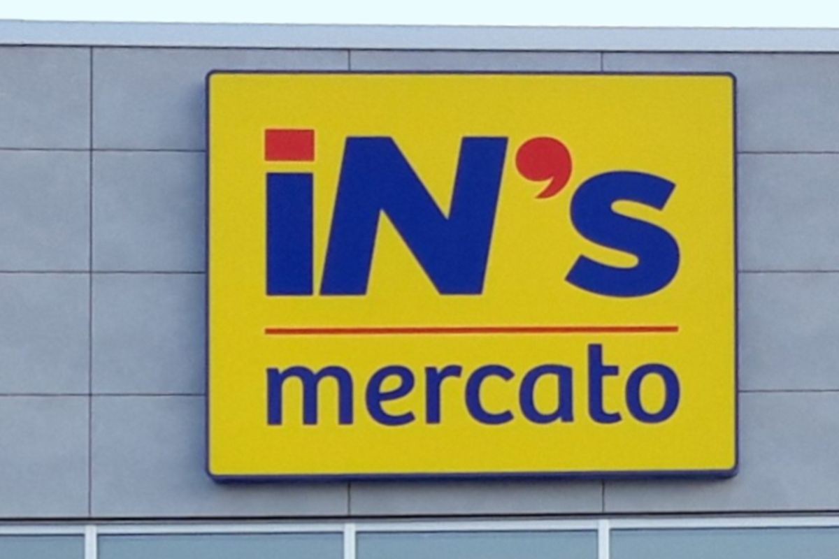 Signboard with 'iN's mercato' in blue letters on a yellow background.